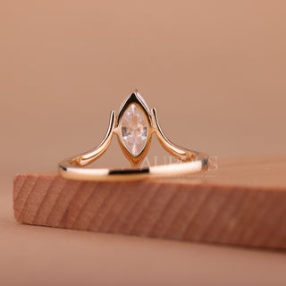 Rose gold ring with a diamond on a wooden block against a beige background