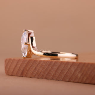 Gold ring with a large diamond on a wooden stand against a beige background